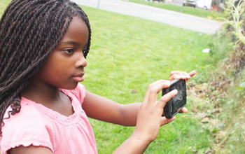 girl taking a photo of a plant with a smart phone